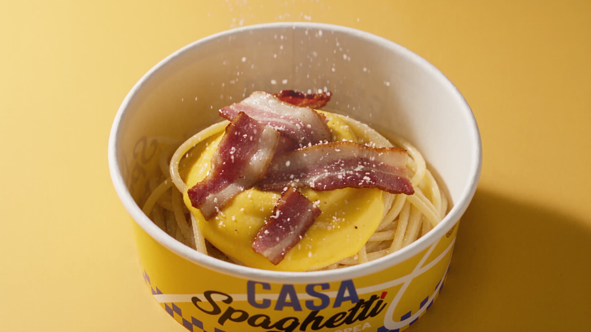 Le fette di guanciale sulla carbonara, con il pecorino grattugiato