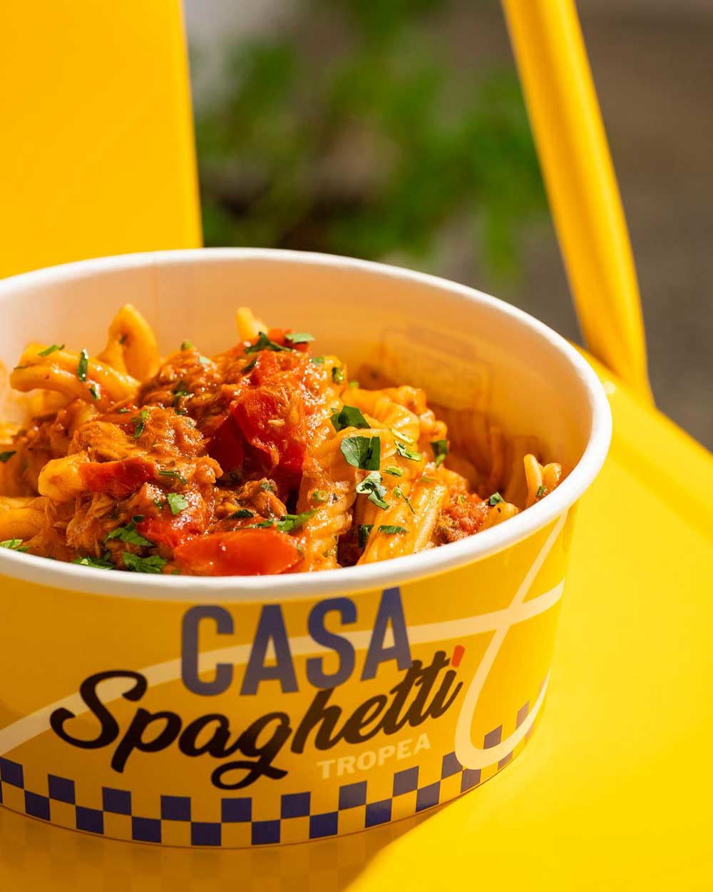 Una ciotola di fileja al pomodoro appoggiata su una sedia gialla