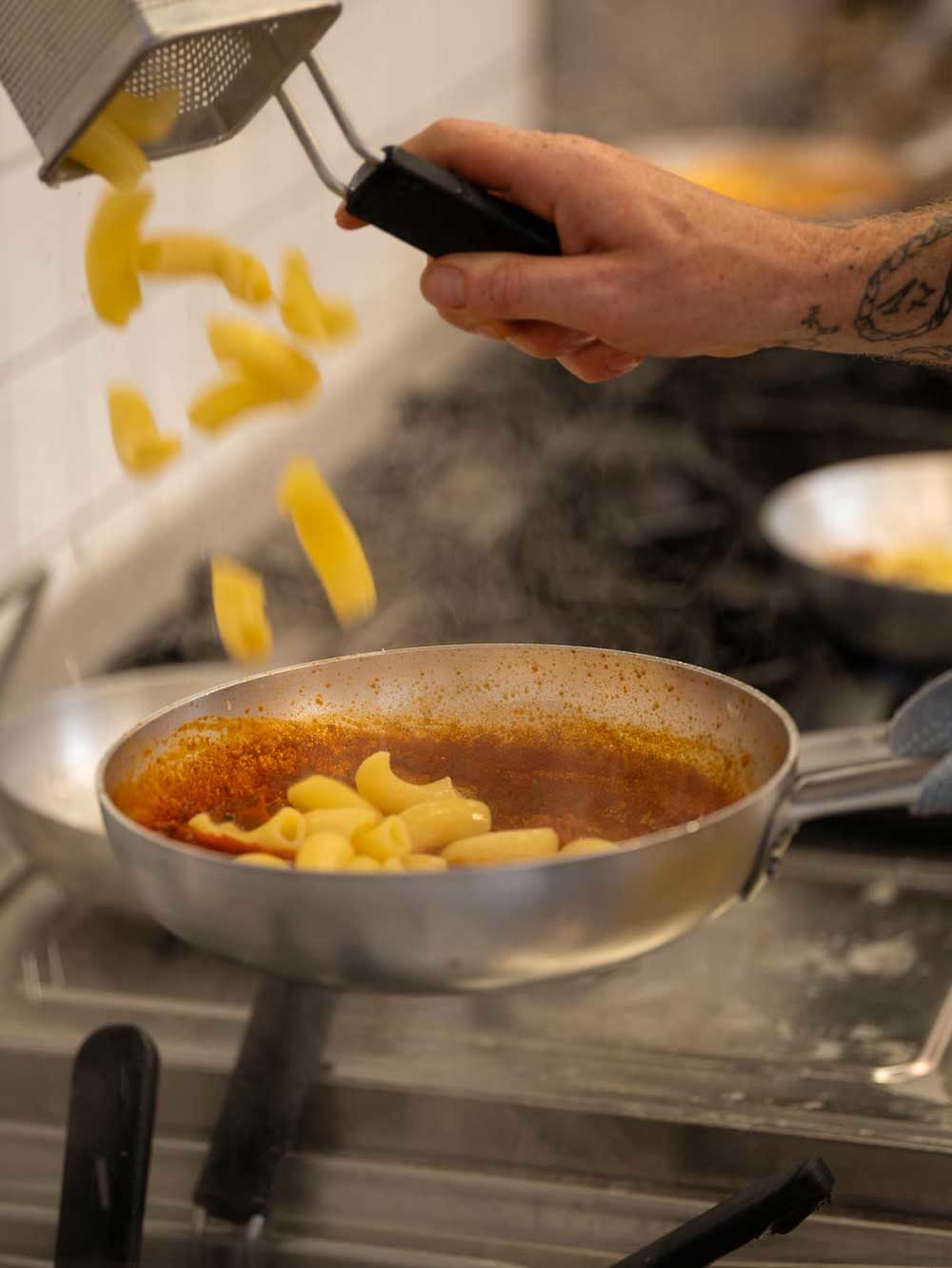 La pasta fresca che scende nella padella con il sugo